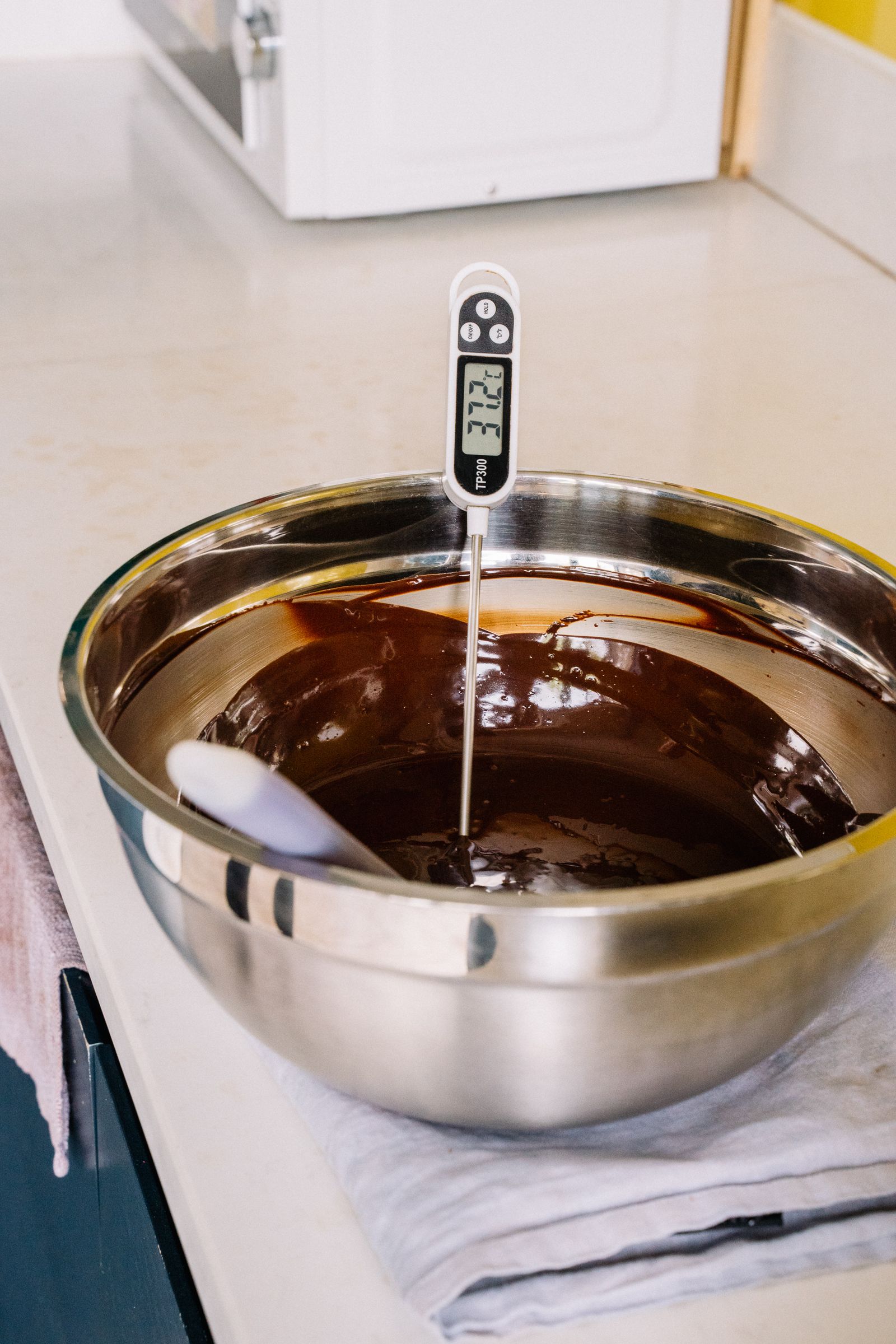 Digital food thermometer resting in a stainless steel bowl in a kitchen.