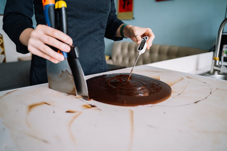 Person Checking The Temperature Of A Chocolate Icing