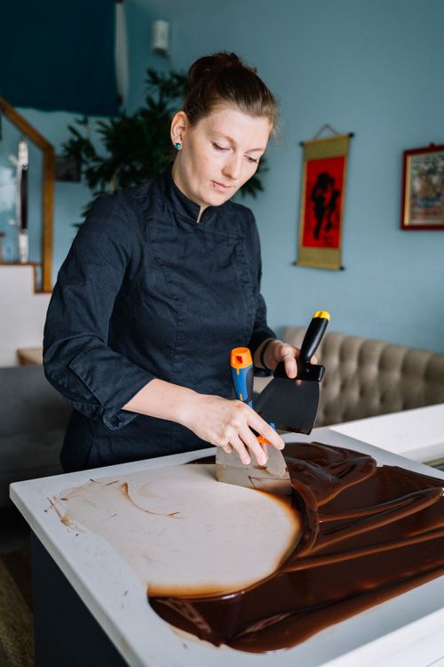Free A female chef skillfully tempers melted chocolate on a countertop in a contemporary kitchen setting. Stock Photo