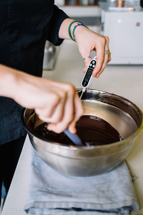 Free Close-up of hands tempering chocolate with digital thermometer in a kitchen. Stock Photo