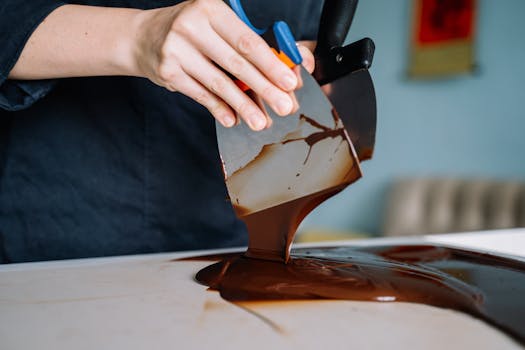 Close-up of chocolate being tempered by hand, showcasing the process of food preparation.