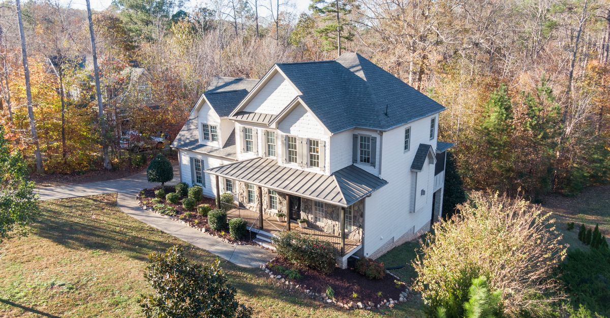 Beautiful aerial view of a charming two-story house in an autumn forest setting in Wake Forest, NC.