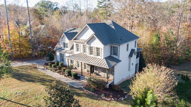 Beautiful aerial view of a charming two-story house in an autumn forest setting in Wake Forest, NC.