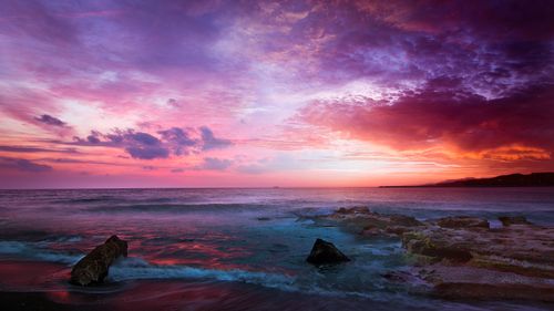 Free Breathtaking view of a vibrant sunset over a rocky seashore with dramatic skies. Stock Photo