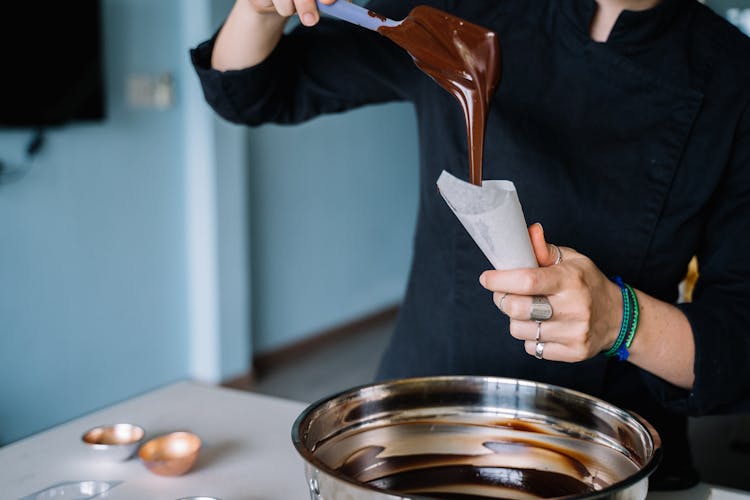 A Person Putting Chocolate Syrup In Piping Bag