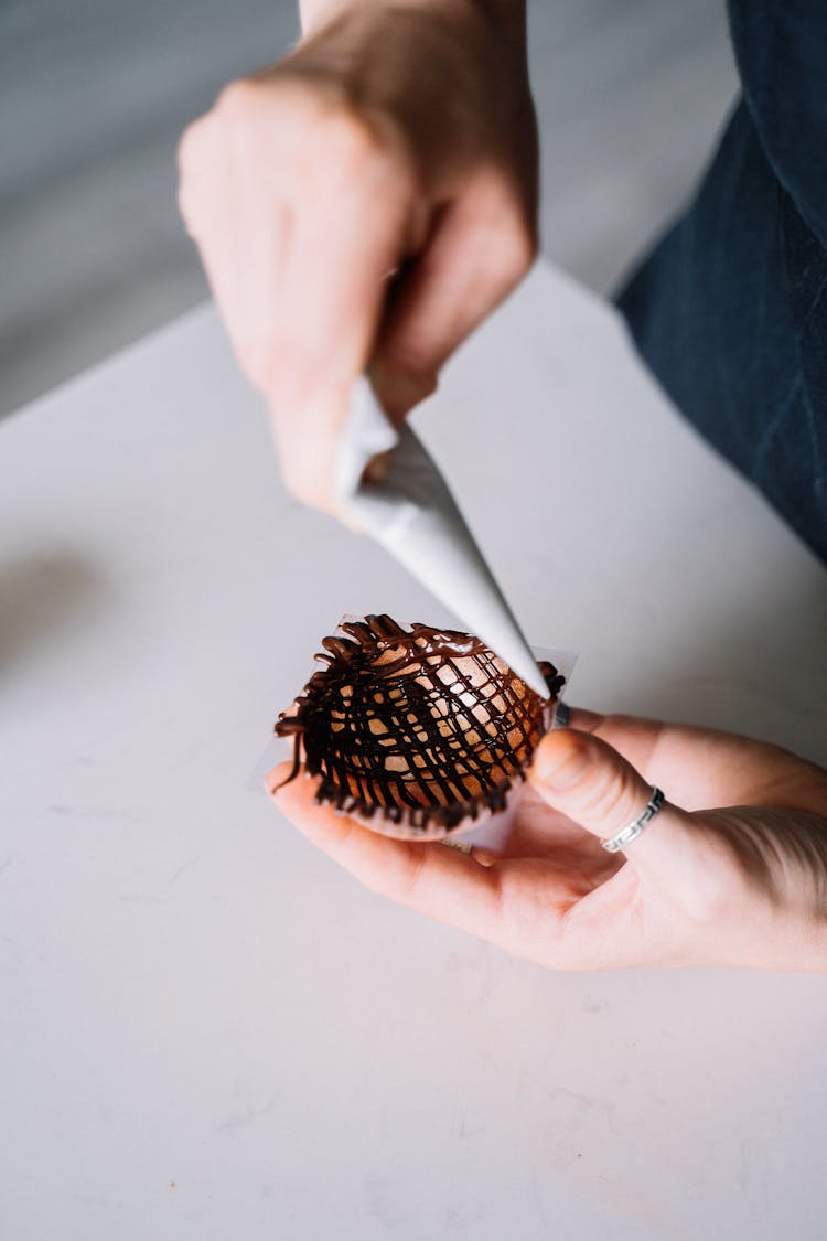 Person Piping Chocolate On A Round Molder 