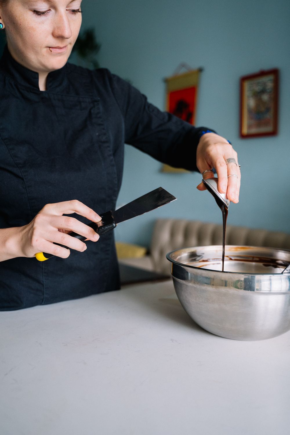 A chocolatier pouring glossy melted chocolate.