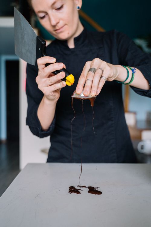 Free Chef expertly tempers chocolate on a flat surface using a scraper for smooth consistency. Stock Photo