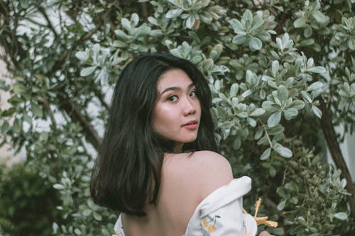 Woman in White Off Shoulder Top Posing near the Green Leaves