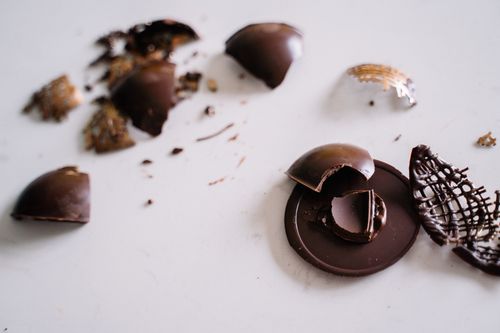 Free Close-up of broken chocolate pieces scattered on a white surface, perfect for food photography. Stock Photo