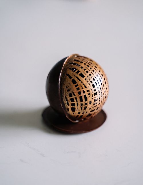 Free Close-up of a chocolate sphere with intricate gold design, perfect for festive occasions and gourmet indulgence. Stock Photo