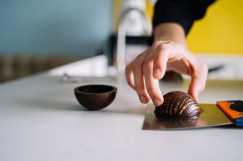 Free Close-up of a person's hand crafting a chocolate dessert in a kitchen setting, showcasing intricate design. Stock Photo