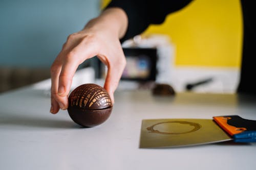 Persona Sosteniendo Baloncesto Marrón Sobre Mesa De Madera Marrón