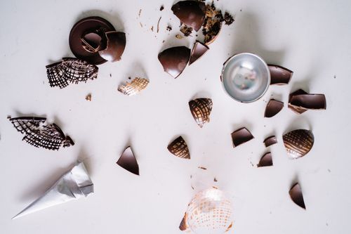Free Scattered broken chocolate pieces on a white background in a flat lay composition. Stock Photo