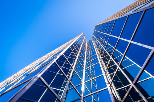 Free From below of facade of tall contemporary skyscraper places in downtown against cloudless blue sky in daytime Stock Photo