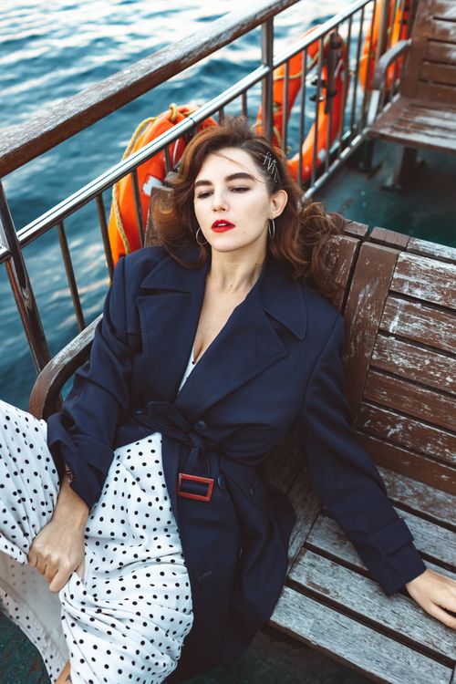 Free Elegant woman in a polka dot dress and navy coat relaxing on a boat. Stock Photo