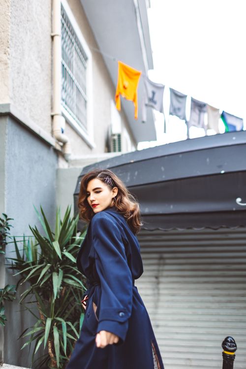 Free A fashionable woman poses in an outdoor setting, exuding elegance and style in a blue coat. Stock Photo