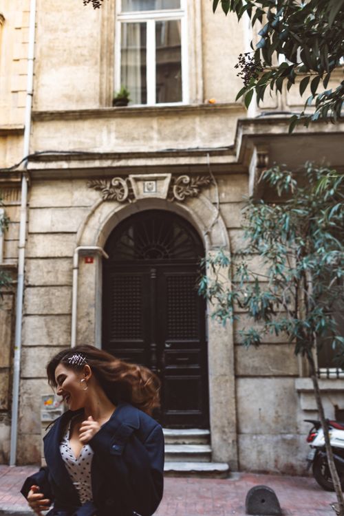 Free A brunette woman joyfully walks past an elegant townhouse entrance on a city street. Stock Photo