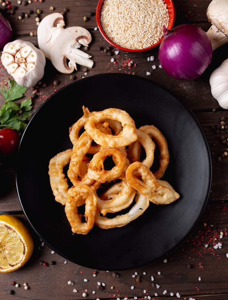 Tasty Calamari Rings On Plate Surrounded With Aromatic Seasonings