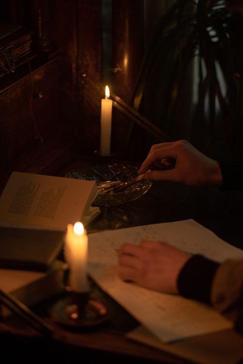 Free A moody candlelit scene with books and an ashtray, highlighting study and contemplation. Stock Photo