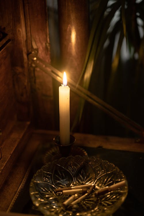 Close-up of Lighted Candle Near Ashtray 