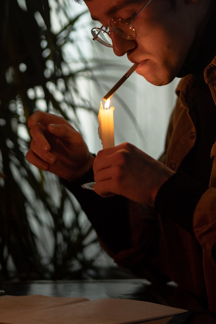 Man Lighting A Cigarette With A Candle 