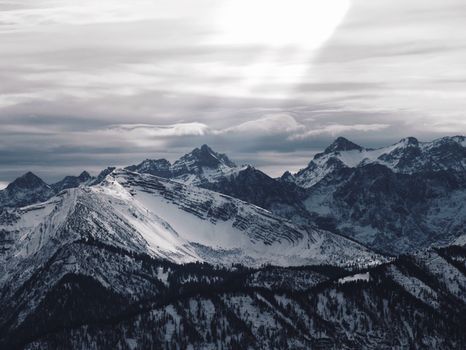 Breathtaking aerial view of majestic snowcapped mountains under a cloudy sky.