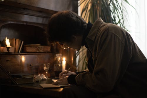 Free Focused Man writing on Paper beside a Candlelight  Stock Photo