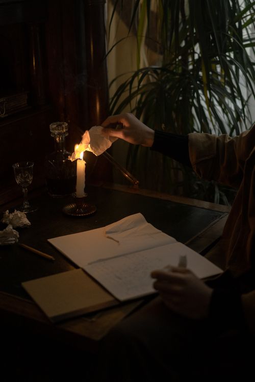 Free An intimate, moody setting with a candle and open notebook, evoking creativity. Stock Photo