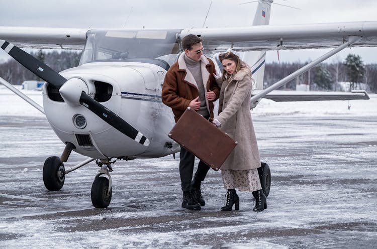 Stylish Couple Standing Close Near Propeller Jet On Airfield