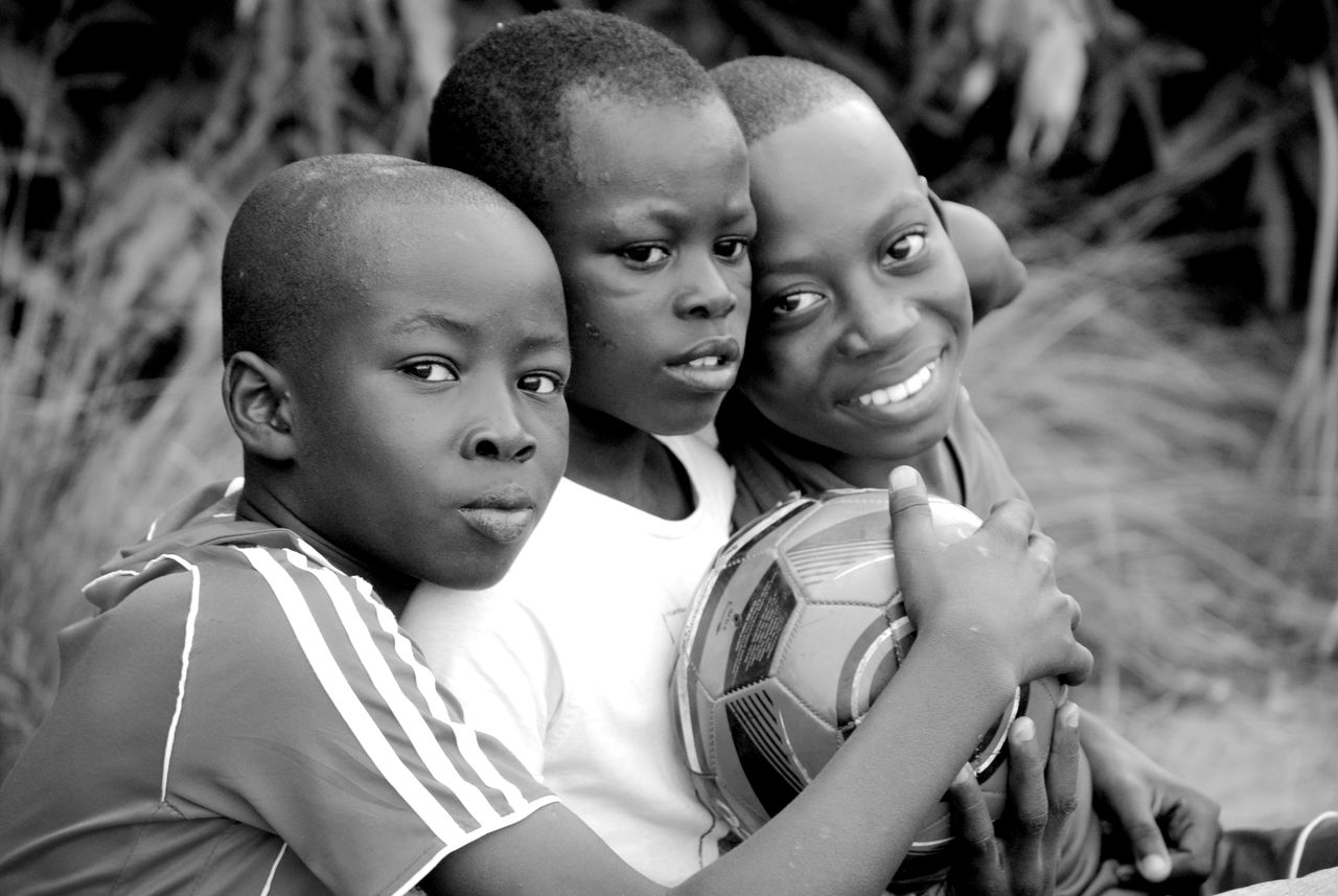 three african boys happily embracing a soccer ball outdoors in togo