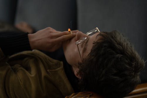 A Man Lying While Smoking Cigarette 