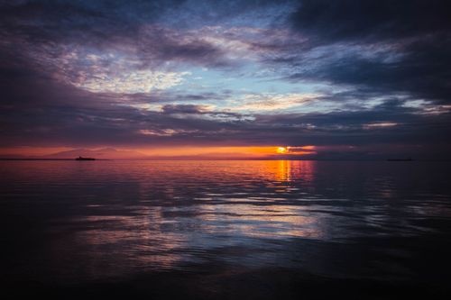 Free A breathtaking view of the ocean at sunset with dramatic skies and calm waters. Stock Photo