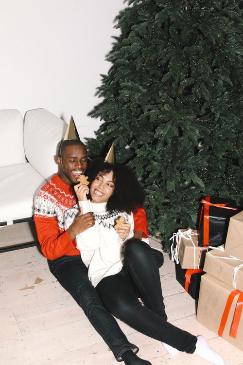Free A happy couple celebrating Christmas indoors with gifts and a festive tree, embracing the holiday spirit. Stock Photo