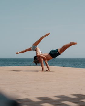 Couple performing acro yoga on a wooden deck by the ocean in Santa Cruz, Spain. Perfect balance and control.