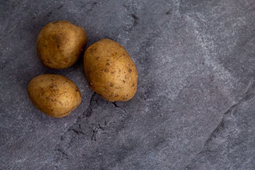 Free Top view of whole unpeeled potatoes placed on rough gray marble table in kitchen Stock Photo