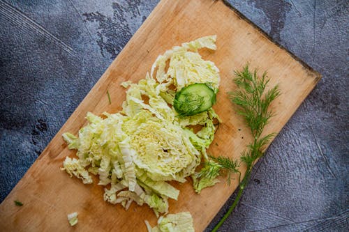 Chopped cabbage on cutting board with herbs and cucumber slice