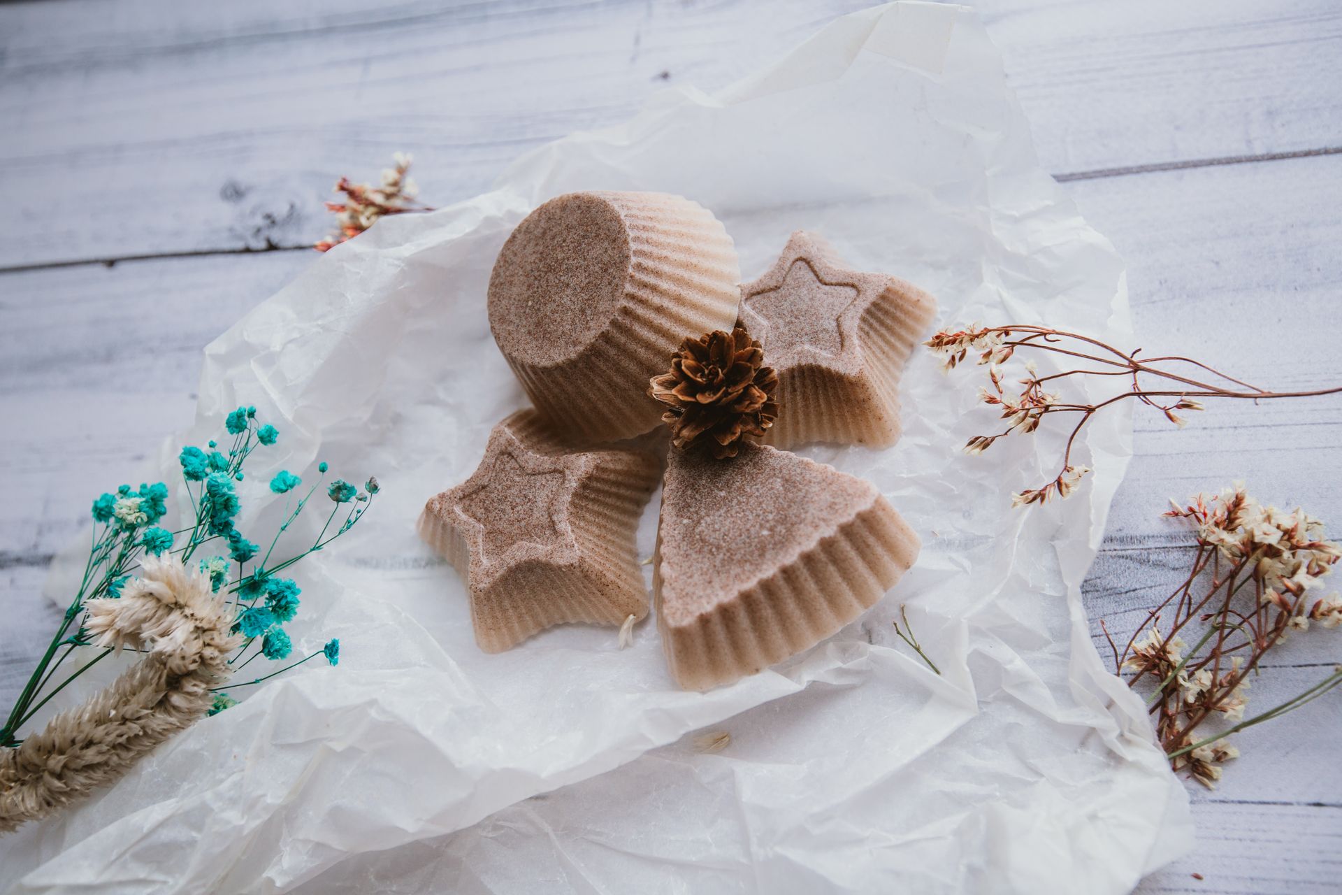 Artistic flat lay of star and cone-shaped soaps with dried flowers, perfect for holiday decor.