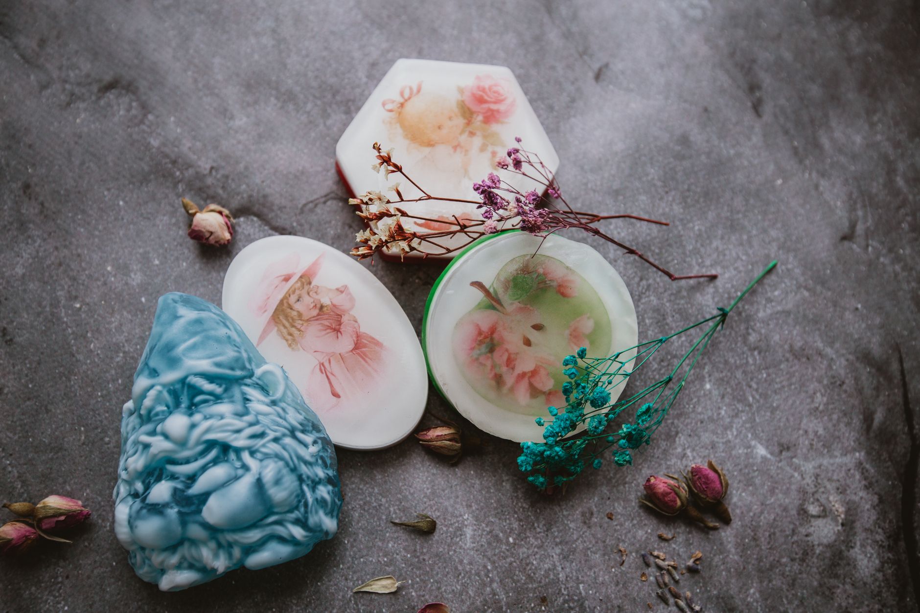 Top view of creative aromatic handmade soaps arranged on gray surface with colorful dried flowers and herbs