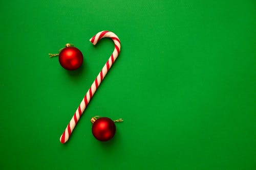 Red Christmas balls with candy stick on green background