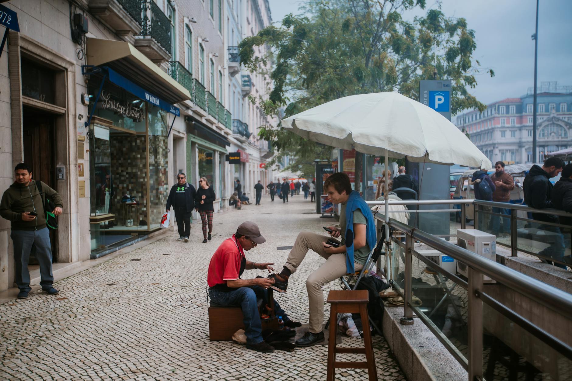 Young shoe shiner polishing boots of male tourist on street
