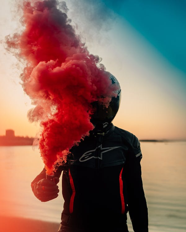 A Person in Black Leather Jacket With Red Smoke on Face · Free Stock Photo