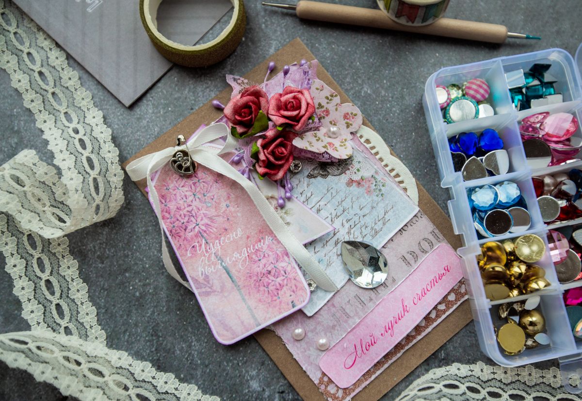Handmade card decorated with beads and buttons beside a box of colorful beads