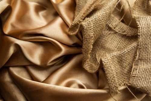 Top view draped golden satin fabric and mesh rattan cane webbing placed on table as background