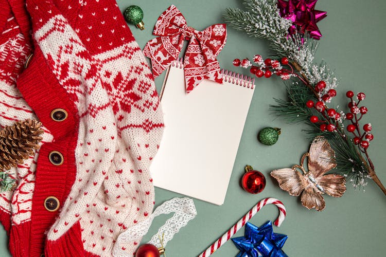 Christmas Decorations And Blank Notepad Arranged With Knitted Cardigan