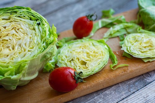 Fresh washed iceberg lettuce and tomatoes on cutting board