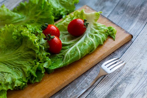 Fresh salad ingredients arranged on wooden cutting board near fork
