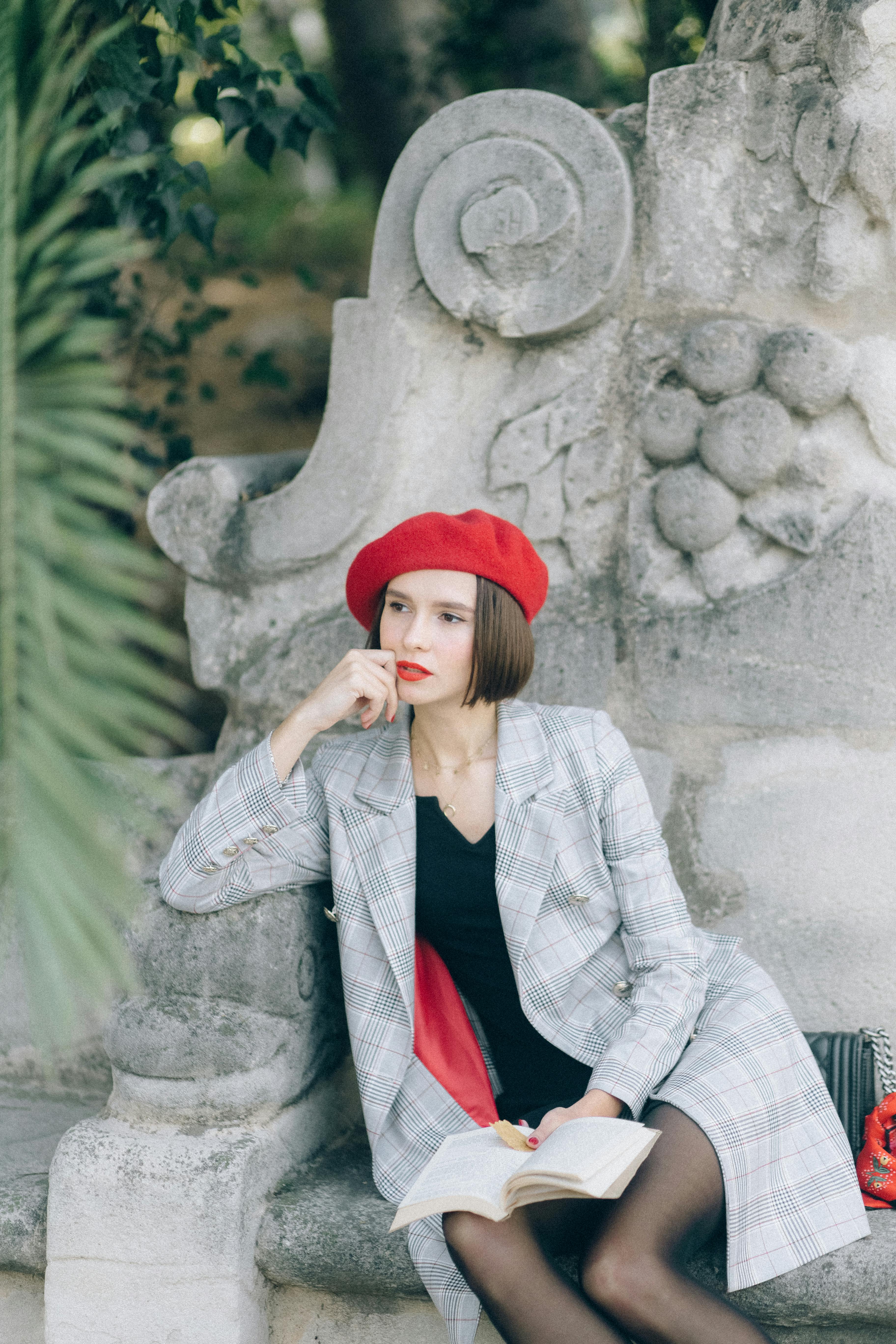 woman in red hat leaning on a statue