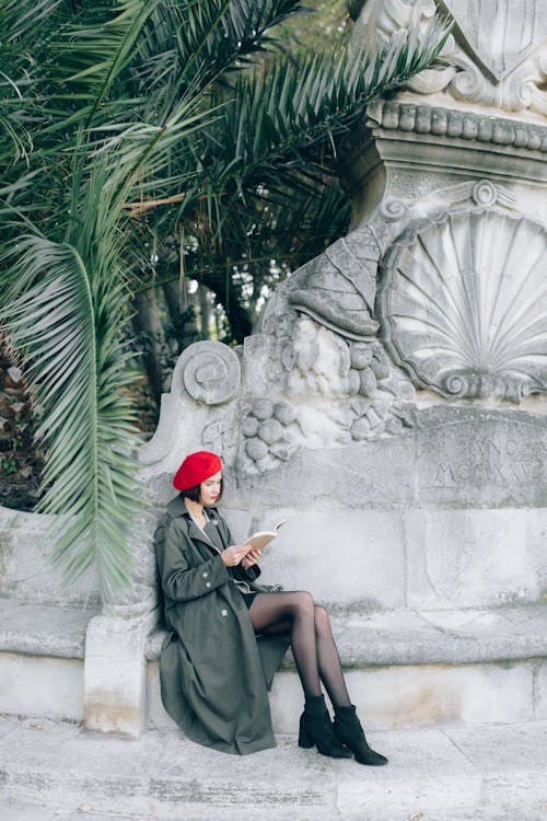 Free Woman in Green Coat Sitting on a Concrete Bench Stock Photo