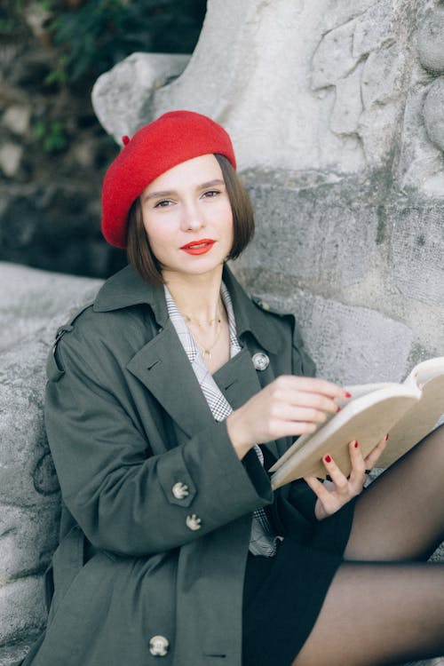 Woman in Black Coat and Red Knit Cap Holding Book · Free Stock Photo